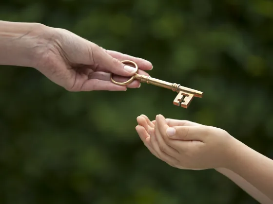 Image of a mother handing a key to her  daughter, hands only